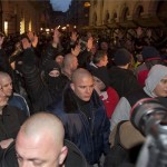 A MEASZ tüntetését megzavarók magasba emelik a karjukat Budapesten, az Új Színháznál