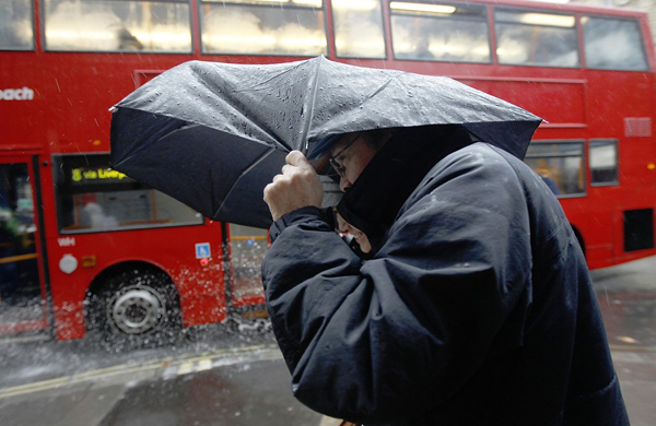 People shelter under an umbrella during heavy rain in central London