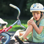 Girl with skinned knee from bike accident