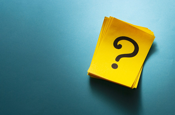 Stack of bright colorful yellow cards with question mark viewed from above on a blue background with copy space